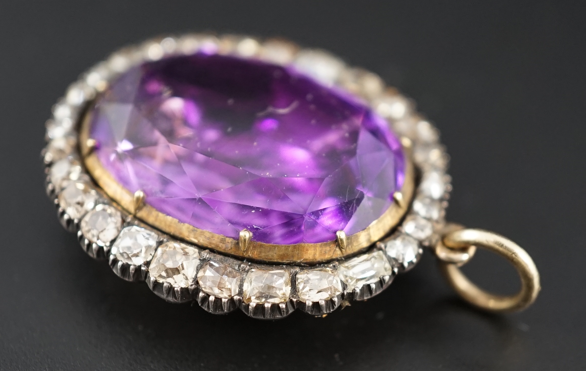 An early 19th century, gold and oval cut foil backed amethyst set pendant, with old cut diamond set border and closed back setting